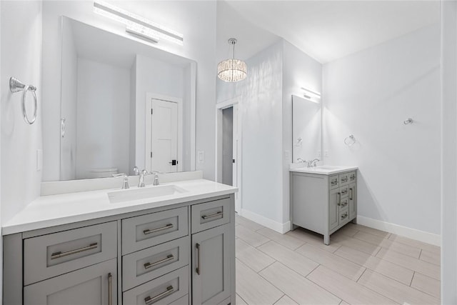 full bath featuring two vanities, baseboards, and a sink