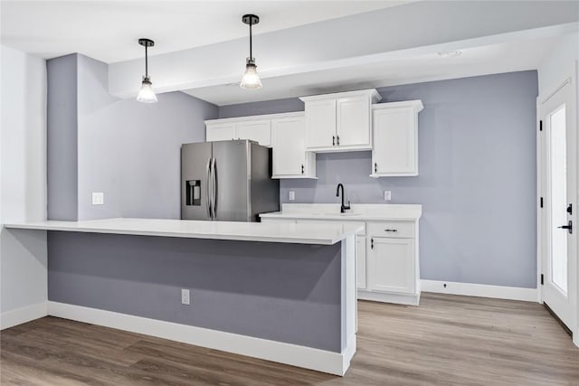 kitchen with baseboards, light countertops, stainless steel refrigerator with ice dispenser, and a sink