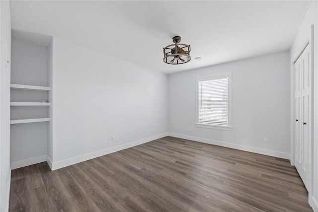 unfurnished bedroom featuring wood finished floors, baseboards, and a closet