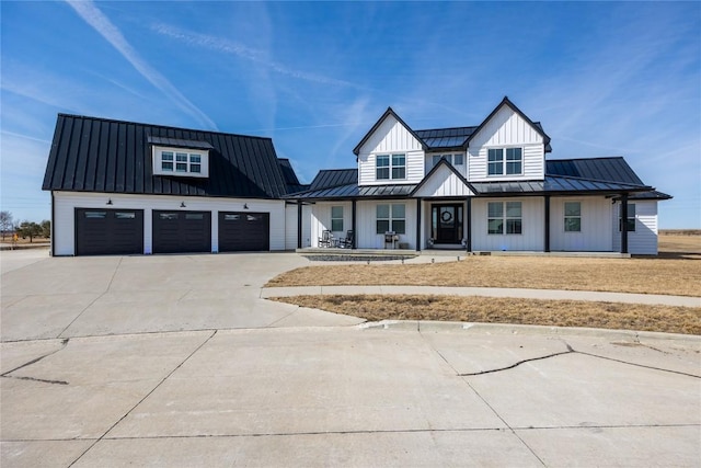 modern farmhouse style home featuring a standing seam roof, concrete driveway, a garage, board and batten siding, and metal roof