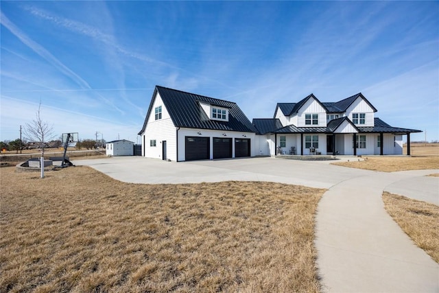 modern farmhouse with a garage, concrete driveway, metal roof, and a standing seam roof