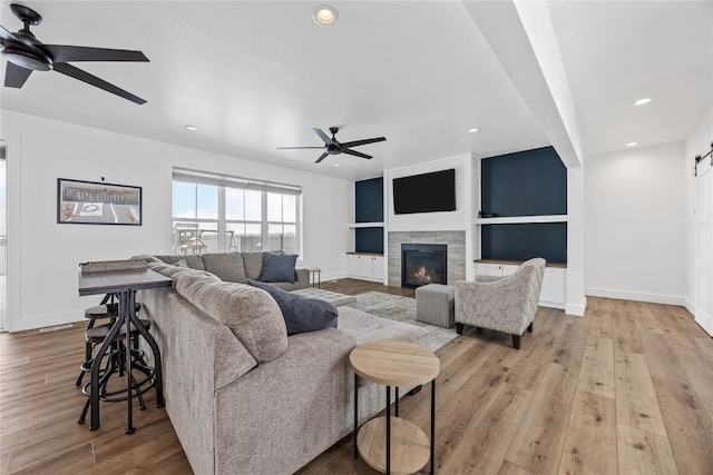 living area featuring baseboards, recessed lighting, a tile fireplace, a ceiling fan, and wood-type flooring