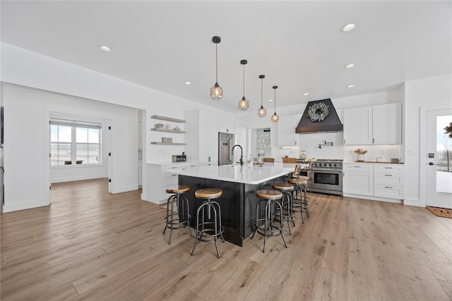 kitchen with light wood-type flooring, open shelves, premium appliances, white cabinets, and custom exhaust hood