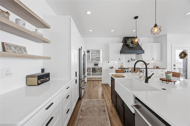 kitchen featuring custom range hood, open shelves, a sink, appliances with stainless steel finishes, and light countertops