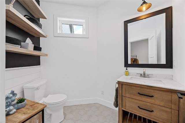 half bath featuring baseboards, toilet, vanity, and tile patterned flooring