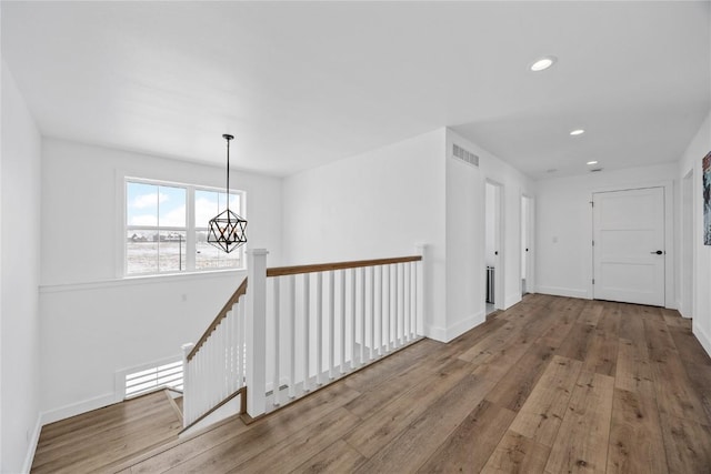 hallway with recessed lighting, visible vents, wood-type flooring, and baseboards