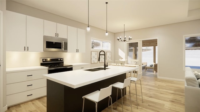 kitchen with light wood finished floors, a sink, appliances with stainless steel finishes, pendant lighting, and a chandelier