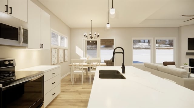 kitchen featuring white microwave, light wood finished floors, a chandelier, electric range, and a sink