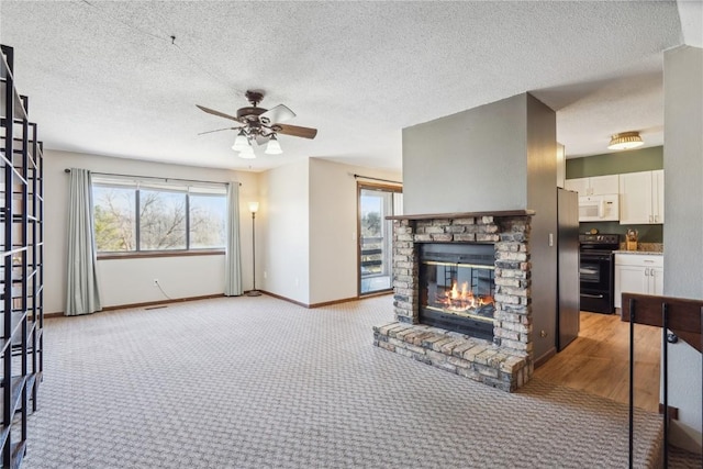 living room featuring baseboards, ceiling fan, light carpet, a glass covered fireplace, and a textured ceiling