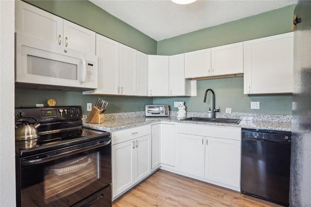 kitchen with black appliances, white cabinets, light wood-type flooring, and a sink