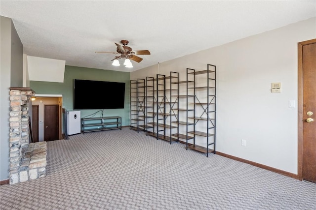 unfurnished living room with carpet flooring, baseboards, and ceiling fan