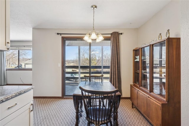 dining space featuring baseboards, light carpet, and an inviting chandelier