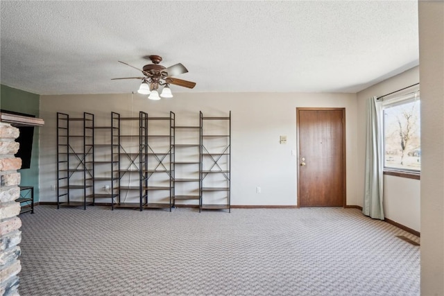 carpeted empty room with a ceiling fan, baseboards, and a textured ceiling