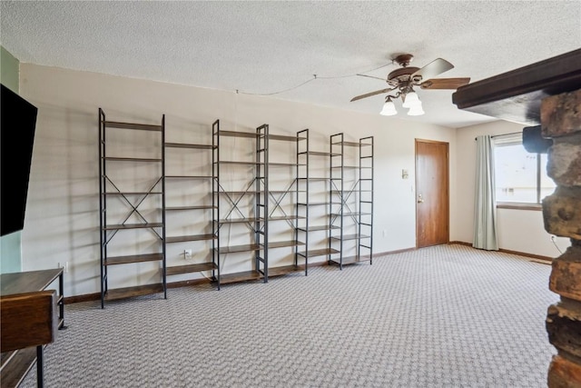 interior space featuring baseboards, carpet flooring, a textured ceiling, and a ceiling fan