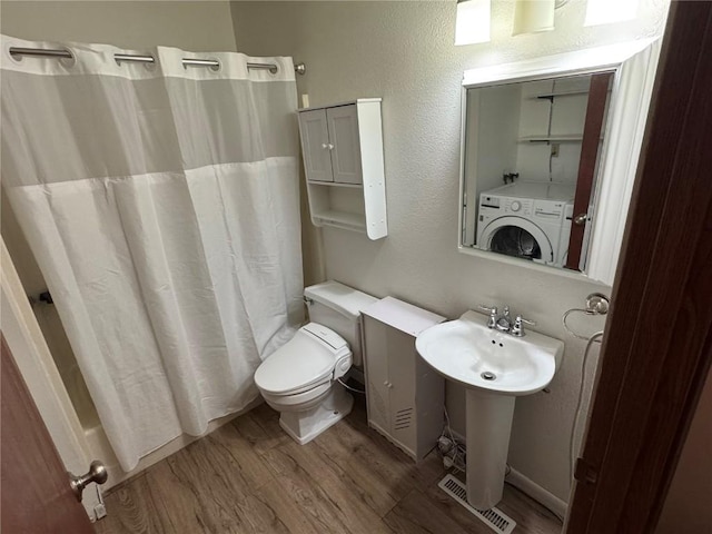 full bathroom featuring visible vents, toilet, shower / bath combo, wood finished floors, and washer / clothes dryer