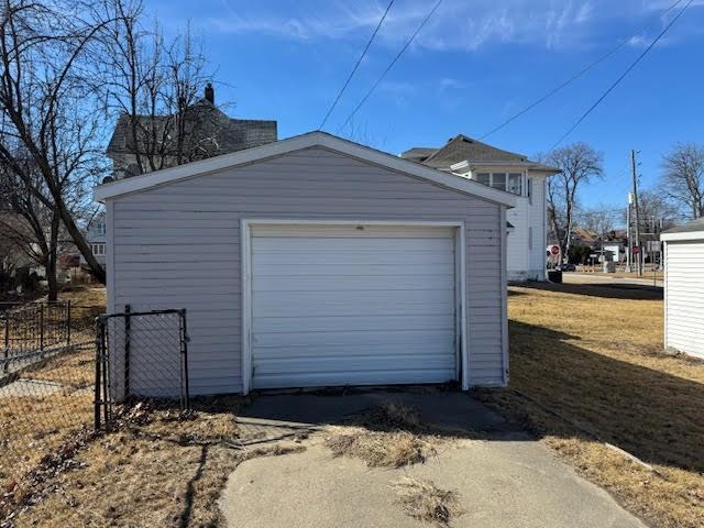 detached garage featuring driveway and fence