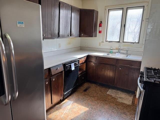 kitchen featuring dark brown cabinets, dark floors, light countertops, appliances with stainless steel finishes, and a sink