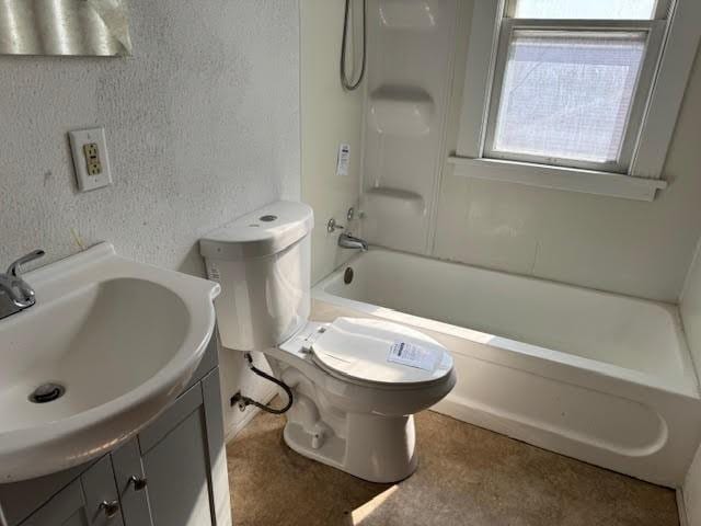 full bath with tub / shower combination, toilet, vanity, and a textured wall