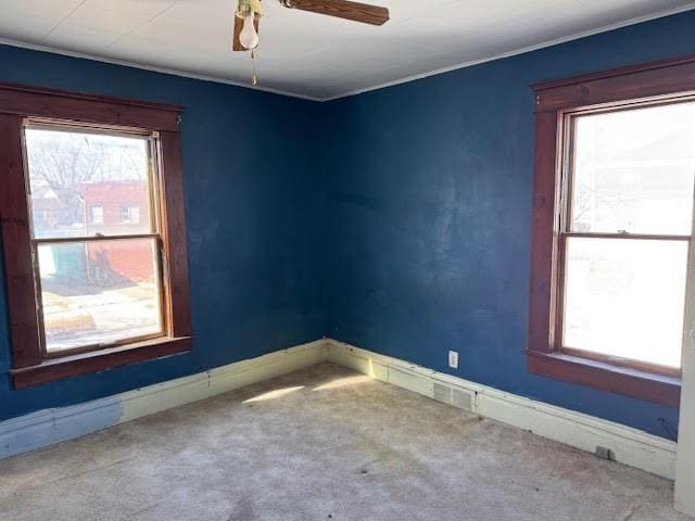 spare room featuring carpet flooring, plenty of natural light, a ceiling fan, and baseboards