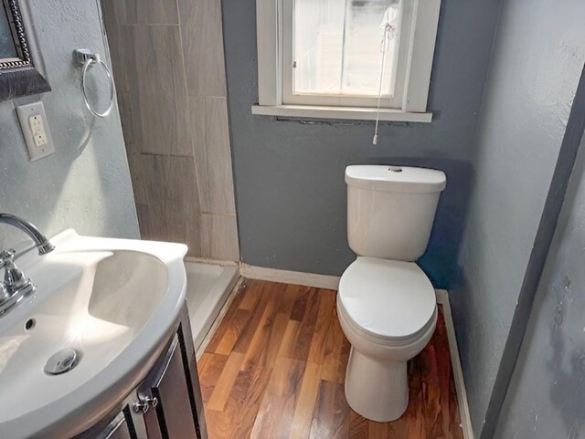 609 Baltimore St, Waterloo, IA 50702 - full bathroom with baseboards, toilet, a stall shower, wood finished floors, and vanity