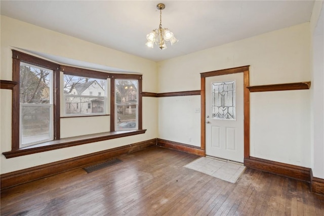 foyer with hardwood / wood-style flooring, baseboards, visible vents, and a chandelier