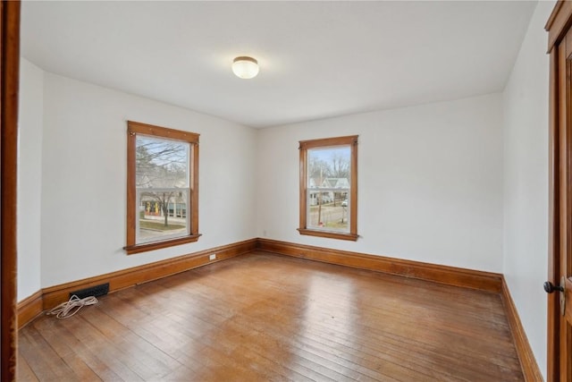 spare room with visible vents, baseboards, and wood-type flooring