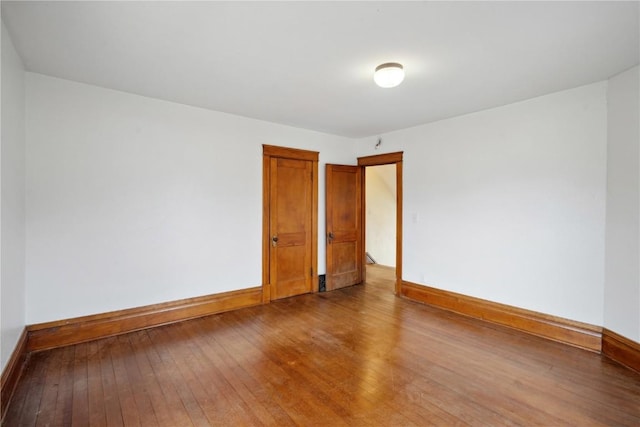 spare room with hardwood / wood-style floors and baseboards