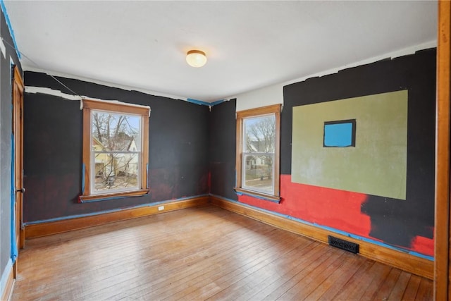 spare room with plenty of natural light, visible vents, and wood-type flooring