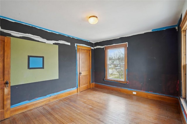 spare room with baseboards and hardwood / wood-style floors