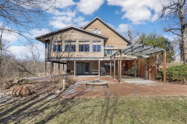 rear view of house featuring a wooden deck, an outdoor fire pit, and a patio