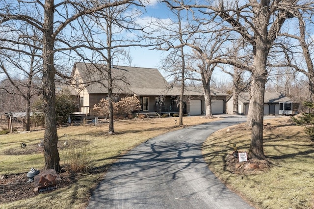 view of front of home with a front yard, an attached garage, a porch, and driveway