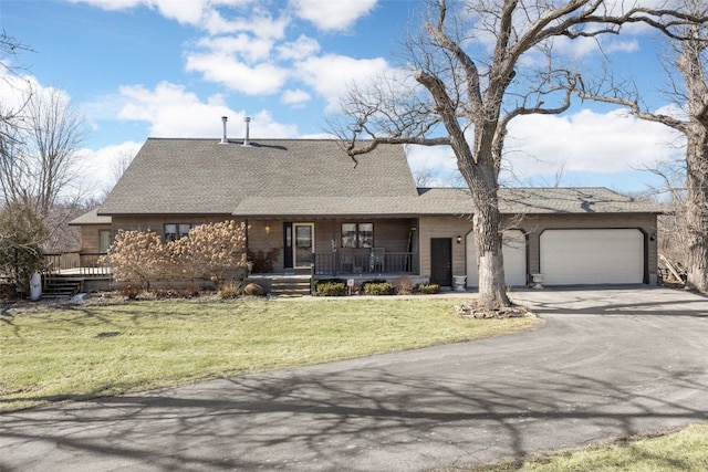 view of front of house featuring a garage, driveway, a porch, and a front lawn