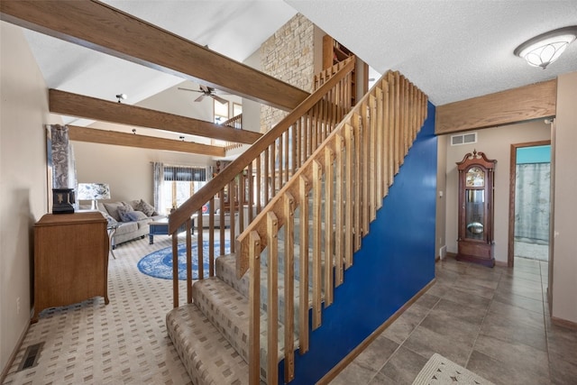 stairs featuring visible vents, lofted ceiling with beams, a textured ceiling, baseboards, and ceiling fan