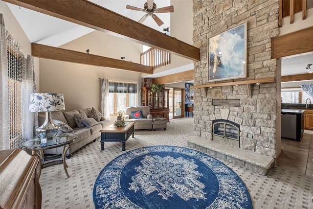 living area with a stone fireplace, beam ceiling, ceiling fan, and high vaulted ceiling