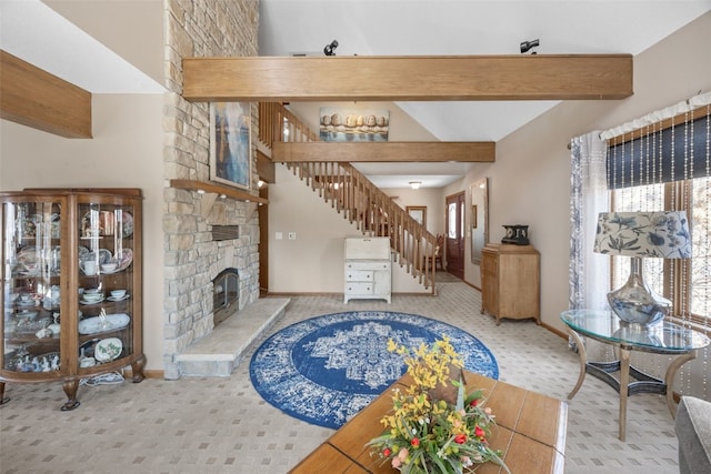 living room with a stone fireplace, beamed ceiling, stairs, and baseboards