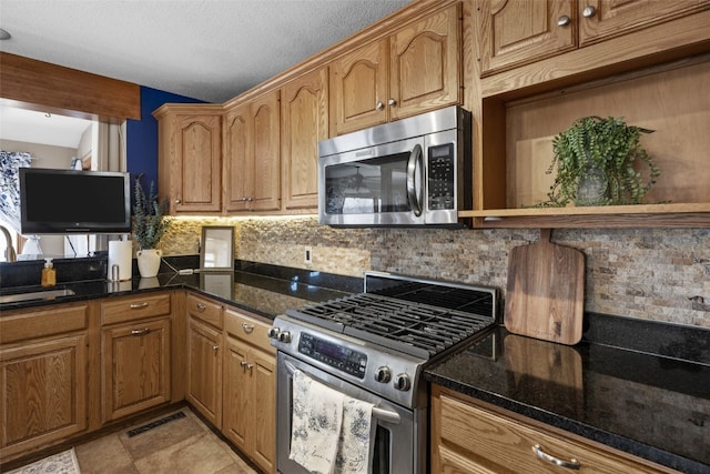 kitchen with decorative backsplash, stainless steel appliances, and dark stone counters