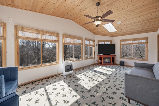 living area featuring heating unit, carpet, baseboards, vaulted ceiling with skylight, and wooden ceiling