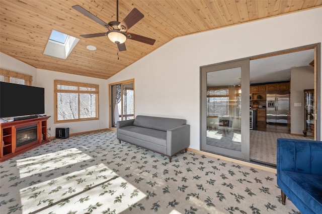 living room featuring lofted ceiling with skylight, light carpet, a glass covered fireplace, baseboards, and wood ceiling