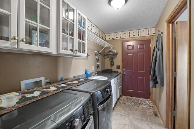 laundry area with visible vents, a sink, a textured ceiling, washing machine and dryer, and cabinet space