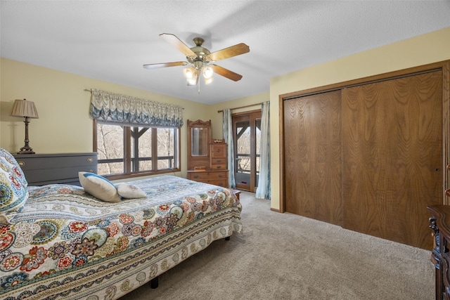 carpeted bedroom with access to outside, a ceiling fan, a closet, and a textured ceiling