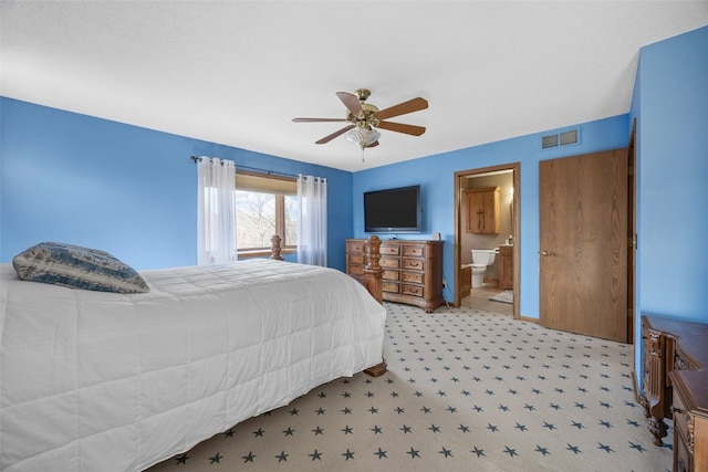 bedroom featuring baseboards, visible vents, ensuite bath, and a ceiling fan