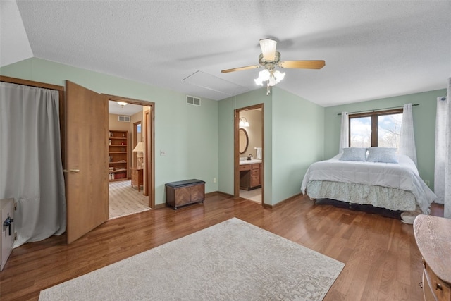 bedroom with ceiling fan, wood finished floors, visible vents, and a textured ceiling