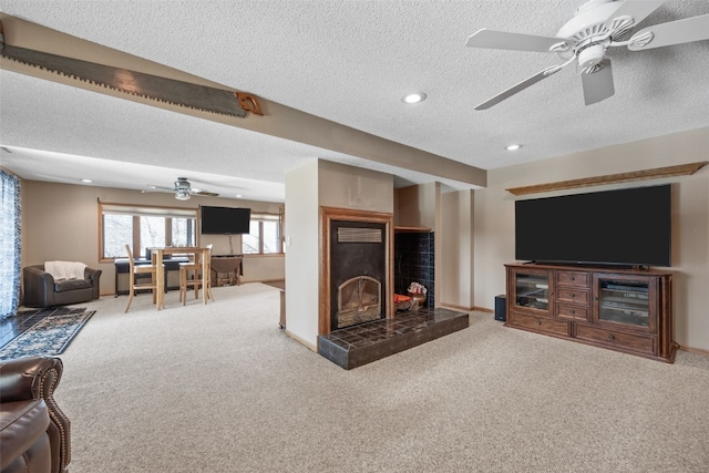 carpeted living area featuring a ceiling fan, a textured ceiling, recessed lighting, a fireplace, and baseboards