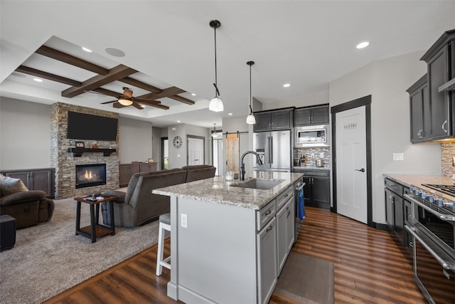 kitchen featuring tasteful backsplash, a barn door, coffered ceiling, high end appliances, and a sink