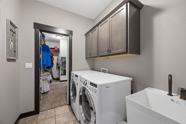 washroom with baseboards, washer and clothes dryer, light tile patterned floors, cabinet space, and a sink