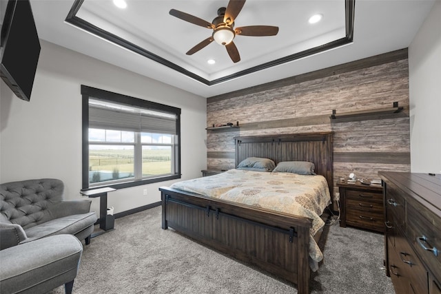 bedroom with baseboards, an accent wall, a tray ceiling, and carpet floors