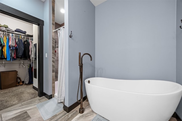 full bath with a freestanding tub, a walk in closet, and tiled shower