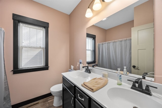 bathroom featuring a sink, visible vents, toilet, and wood finished floors