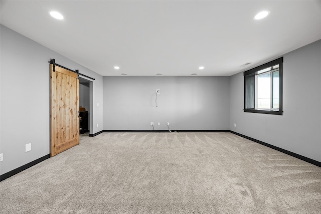 carpeted spare room with recessed lighting, a barn door, and baseboards