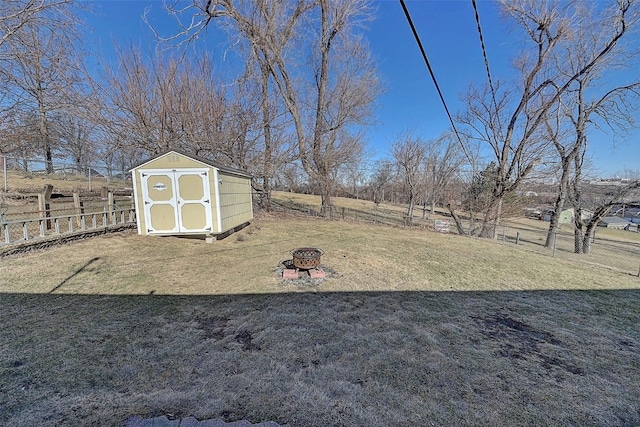 view of yard with fence, an outdoor structure, an outdoor fire pit, and a shed